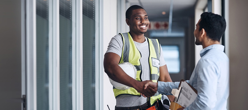 Construction employee shaking hands with business owner in an office